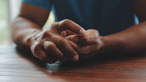 close-up of hands clasped on a wooden table