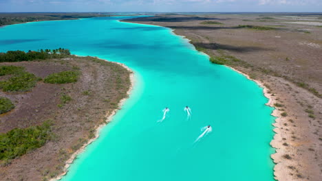 Jagen-Einer-Drohnenaufnahme-Von-Jet-Skifahrern-Im-Klaren-Blauen-Wasser-Von-Bacalar,-Mexiko