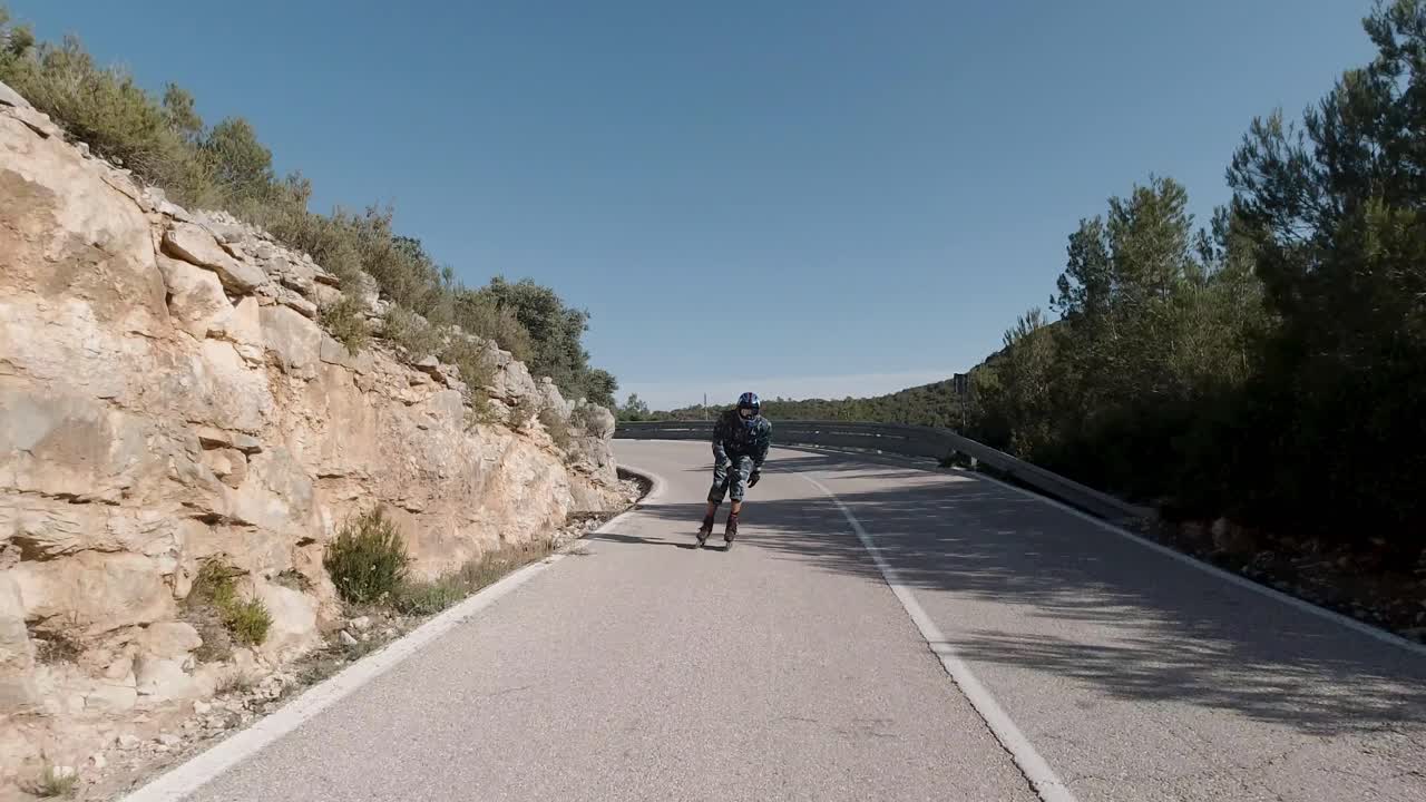 Front facing follow shot of roller skater taking left turn on mountain road