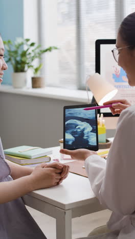 doctor showing ultrasound to pregnant woman