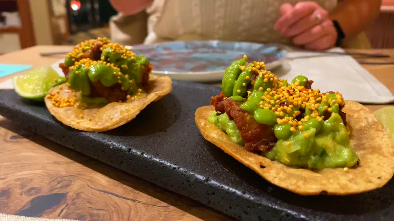 recoger una sabrosa memela con pancita confitada y salsa verde picante, comida tradicional de la cocina mexicana en un restaurante, tacos de vientre de cerdo, tiro de 4k
