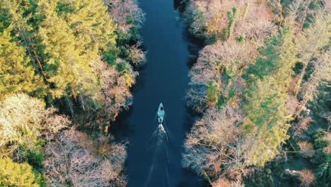 Atemberaubende-Luftaufnahme-Eines-Bootes,-Das-Im-Herbst-Den-Fluss-Hinunterfährt