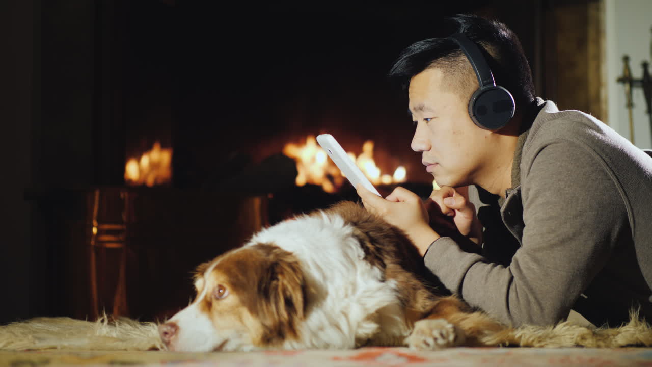 아시아 남자는 벽난로 근처에 태블릿을 사용합니다 01