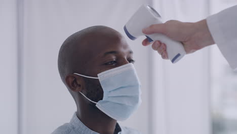 Man-having-his-temperature-checked-while-wearing