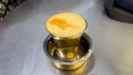 close-up of south indian filter coffee with rich froth in a traditional brass tumbler