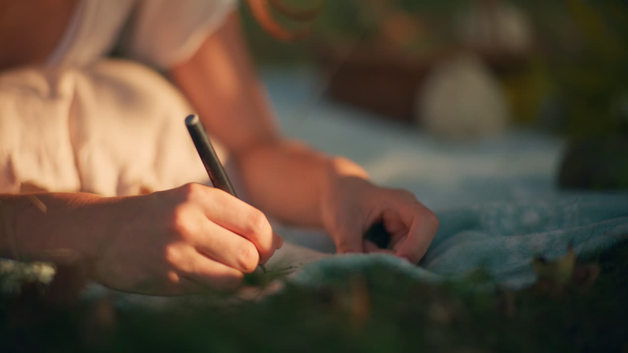 Closeup of hand writing dreams on picnic blanket