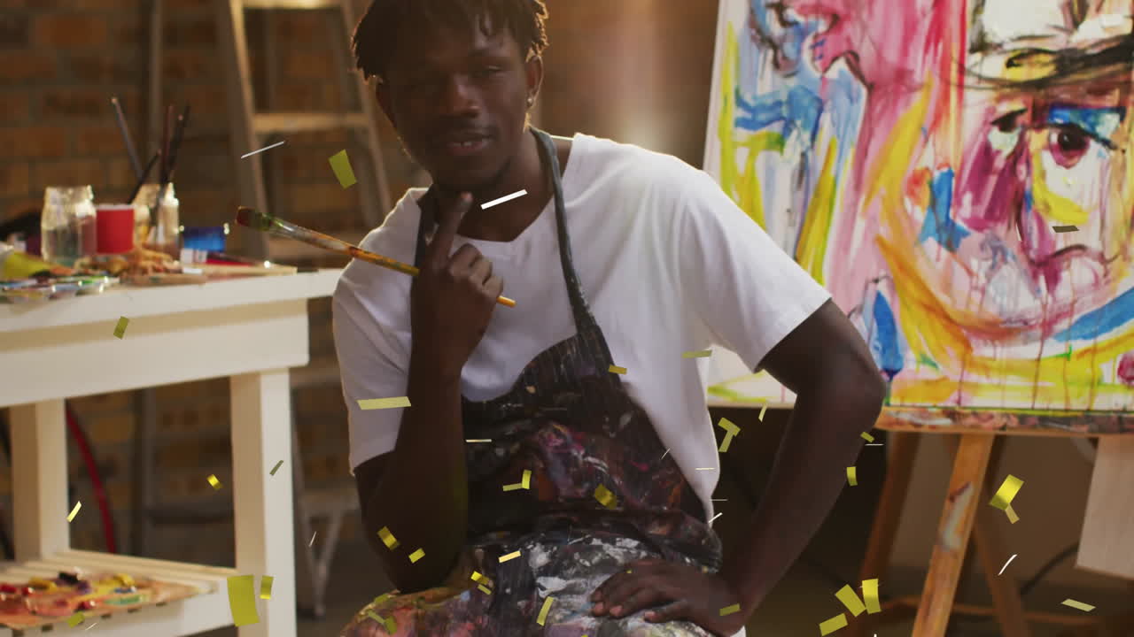 Artist sitting thoughtfully in studio with colorful painting and confetti animation