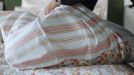 a woman making her bed with floral bedding