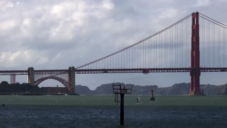 distant windsurfer speeds across rough water into the sun in front of the golden gate bridge in san francisco