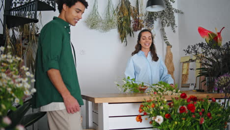 el hombre africano compra flores en una pequeña tienda de flores. la mujer florista vende trabajo.