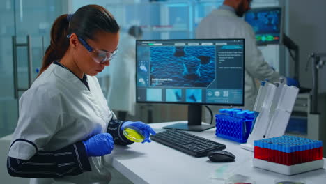 chemist with protection glass examining various bacteria holding petri dish