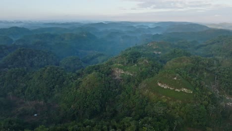 Aerial-establishing-shot-of-idyllic-Los-Haitises-National-Park-with-green-mountains-during-foggy-morning---backwards-flyover