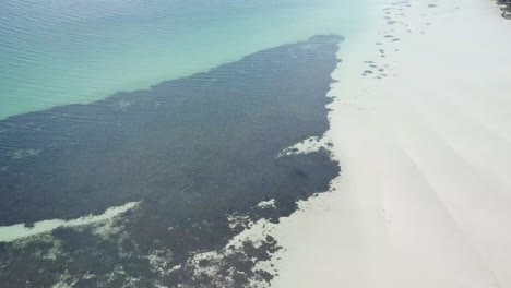 Drone-flying-over-crystal-clear-blue-water