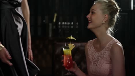 female friends interacting with each other while having cocktail