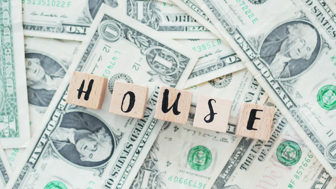 rotating word house from wooden letters, on dollars, concept