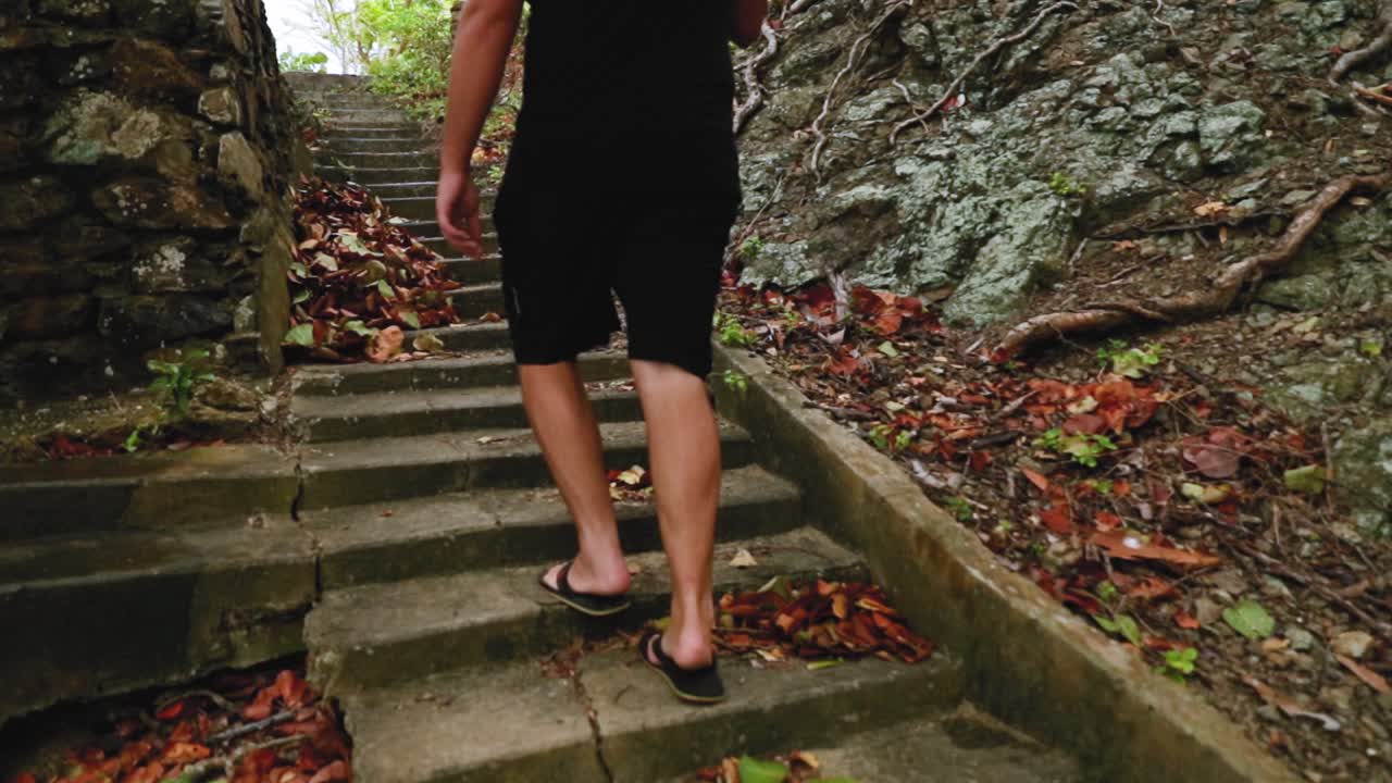 Man walking up concrete stairwell in the forest which is remnants from an abandoned building
