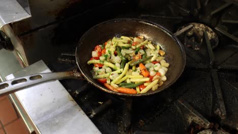 chef cooks a variety of vegetables in a pan on a stove