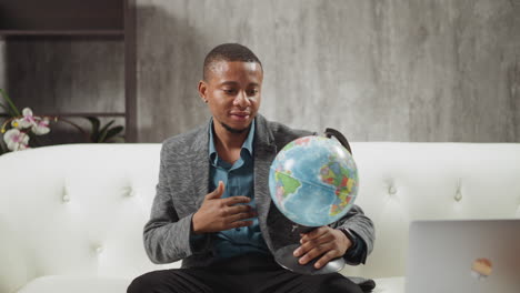 african-american geography teacher turns globe on couch