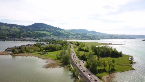 aerial view of a scenic highway bridge over a lake with mountains in the background