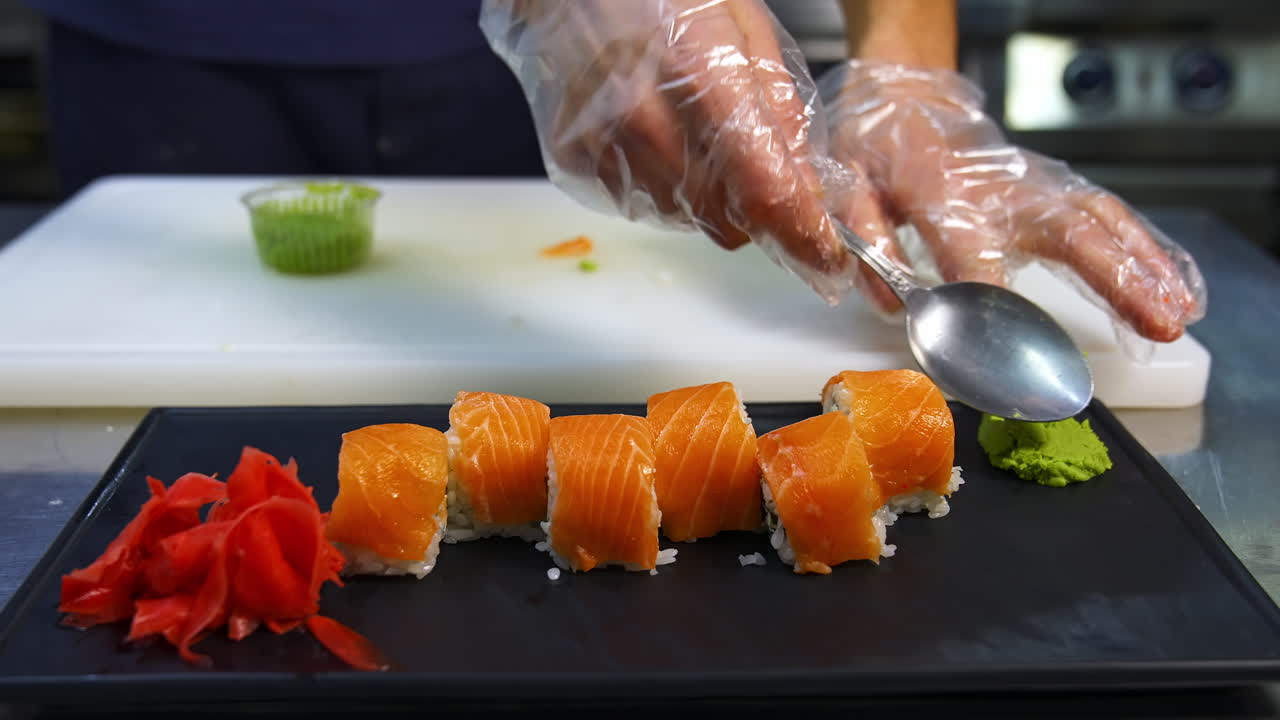 Professional chef hand decorate sushi roll on a serving plate to custom. Chef preparing delicious sushi menu fish with rice in japanese restaurant.