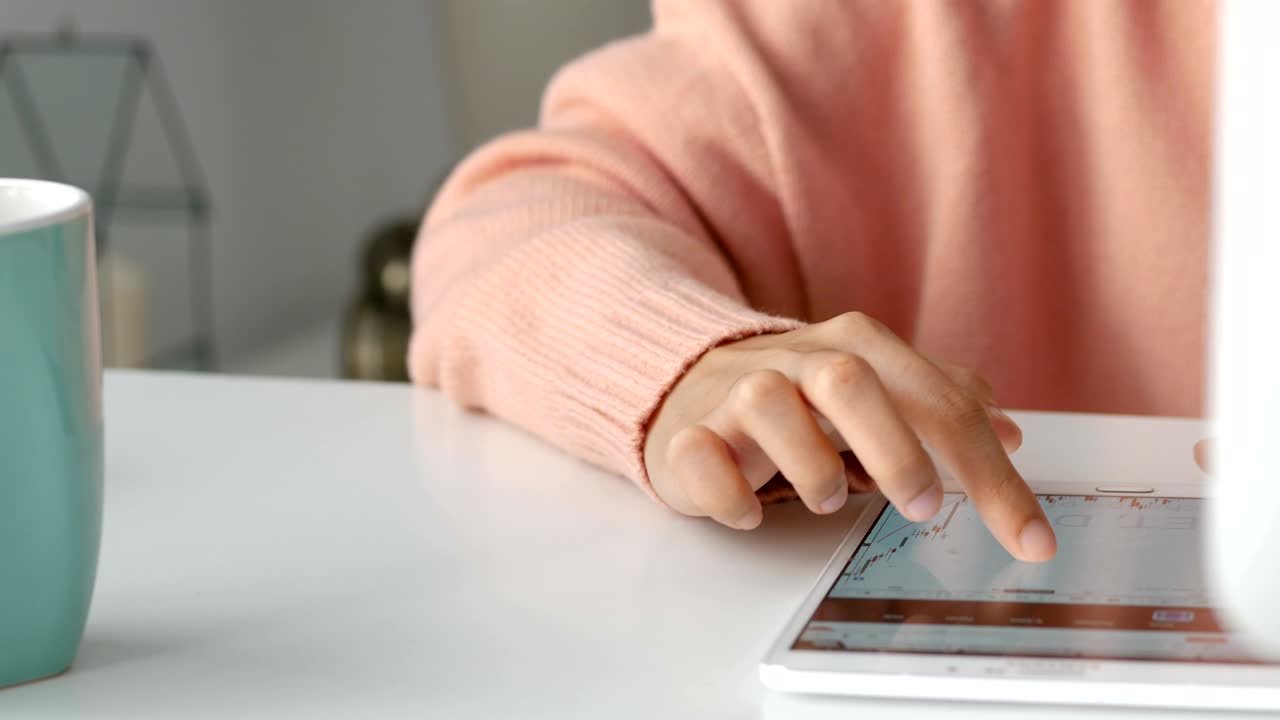 cerrar a jóvenes mujeres asiáticas dueñas de negocios usando una aplicación de teléfono inteligente y jugar a la bolsa de valores en la oficina.