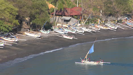 a catamaran style boat motors into a sandy beach