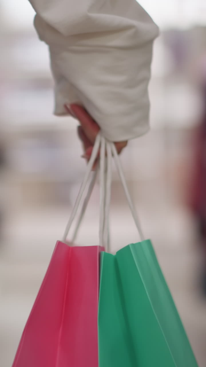 vista de cerca de la pierna de una compradora caminando con confianza a través de una tienda de ropa al por menor, llevando bolsas de compras rosas y verdes vibrantes, con pantalones vaqueros casuales y una camiseta blanca