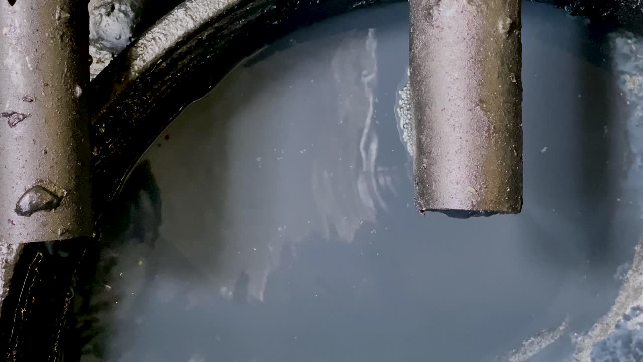 Black chemical wastewater coming out from pipe to storage tank from industrial processes