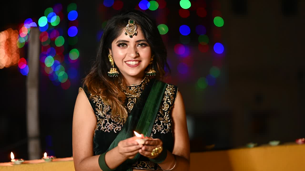 una joven hermosa encendiendo una lámpara de aceite en ropa tradicional con ocasión de diwali.