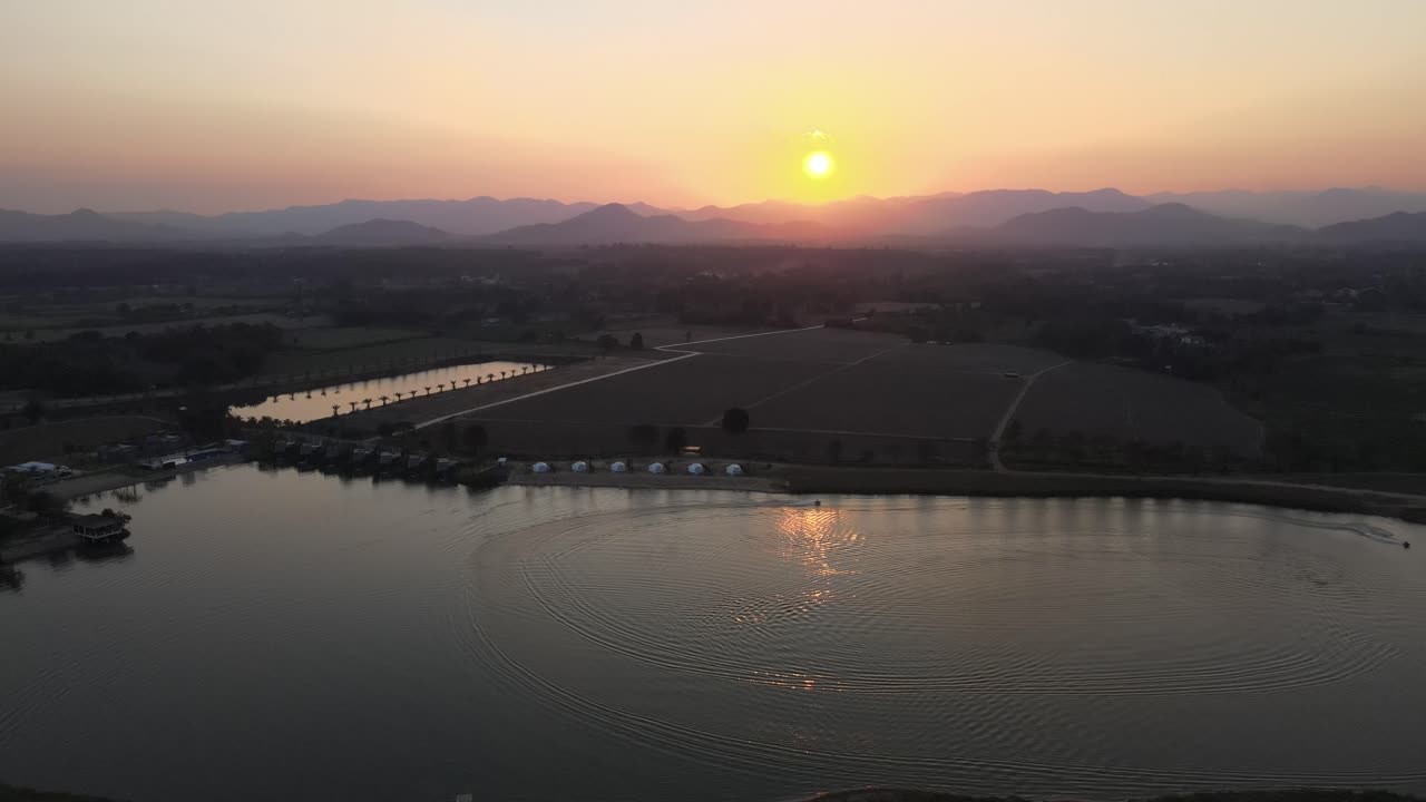 Beautiful Orange Sunset with Jet Skis on a Lake in Thailand. Aerial Drone Shot with Dolly and Tilt Down Movement.