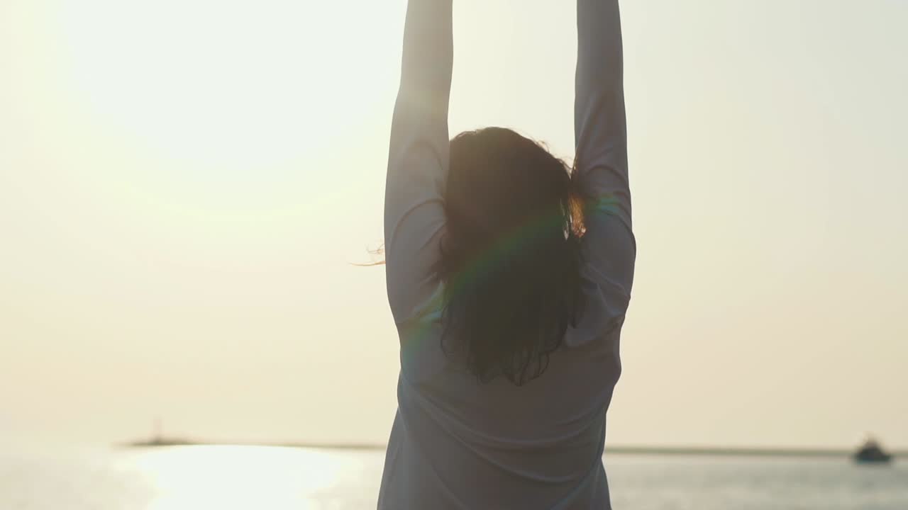 una mujer disfrutando de la puesta de sol junto al océano.