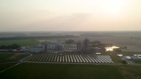 Granja-De-Alta-Tecnología:-Campo-De-Hierba-Y-Silos-Agrícolas-Con-Un-Campo-De-Paneles-Solares-De-Drones-Aéreos