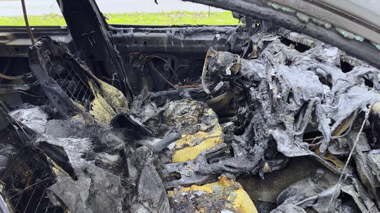 Innenansicht einer zerstörten Autokabine in Arnhem, die ein geschmolzenes Armaturenbrett und skelettartige Sitze nach einem verheerenden Fahrzeugbrand zeigt.