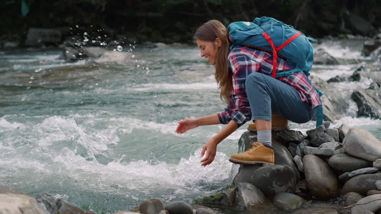 mujer tomando un descanso en el río en las montañas. niña feliz salpicando agua en el aire