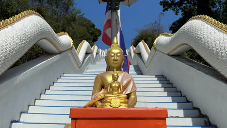 golden buddha statue on naga staircase of wat phlong sawai - buddhist temple on hill in rayong, thailand. closeup shot