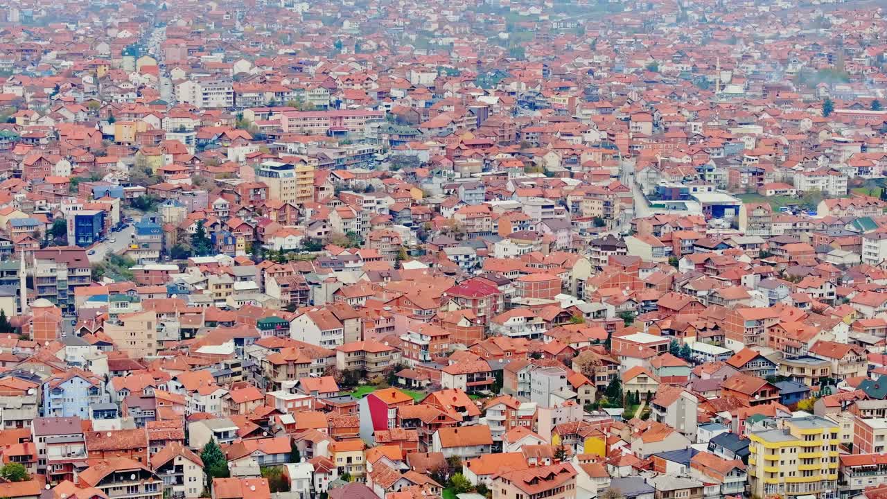 Establishing Shot, forward drone above Pristina rooftops in soft autumn daylight