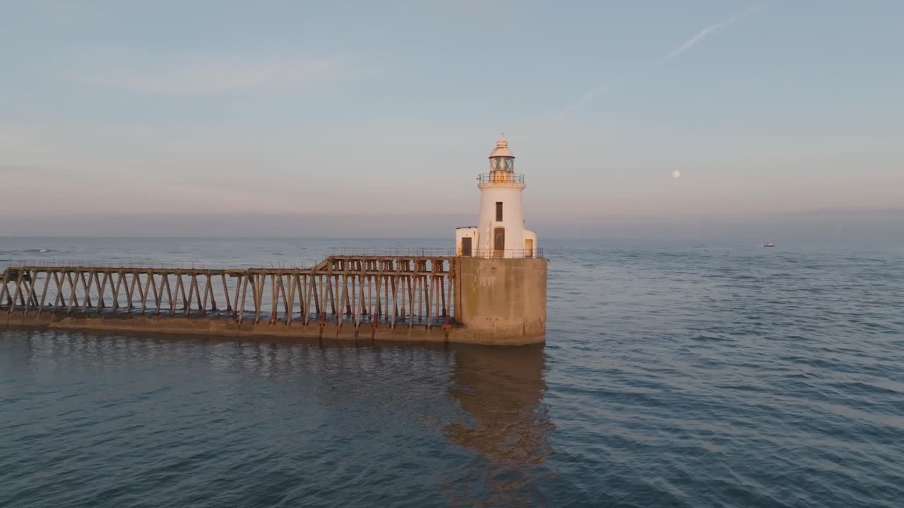 Pastel coastal skies with gradient of colour, with lighthouse and calm sea