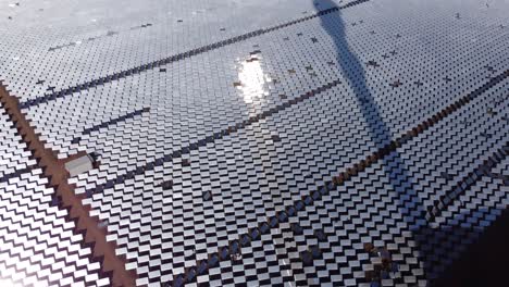 a tilt down shot of a solar farm with thousands of heliostat mirrors reflecting sunlight
