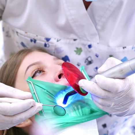 doctor treats patient teeth in modern dental clinic. photopolymer lamp in male doctor's hands.