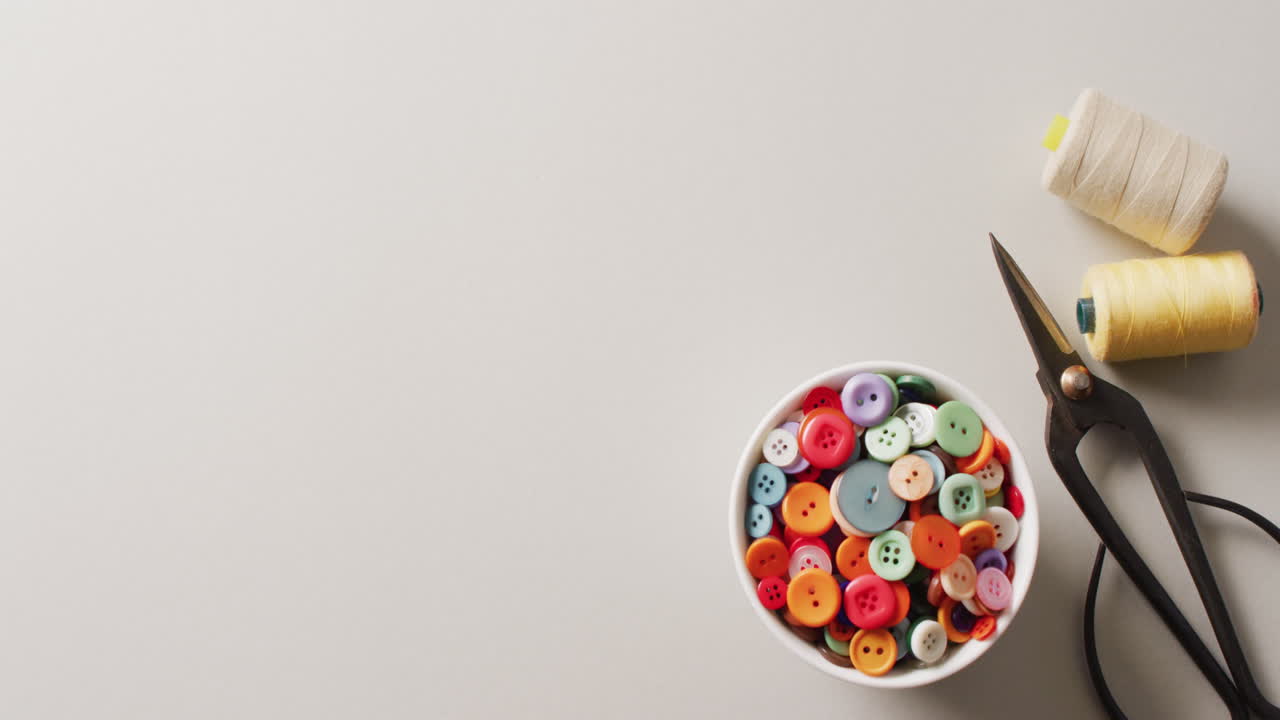 video de cortadores de hilo, un cuenco de botones y carretes de hilo en fondo blanco con espacio de copia
