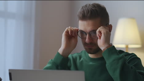 Der-Junge-Mann-Arbeitet-Zu-Hause-Mit-Einem-Laptop-Und-Setzt-Eine-Brille-Auf,-Um-Gut-Sehen-Und-Die-Augen-Schützen-Zu-Können.-Porträt-Des-Mannes-Im-Zimmer