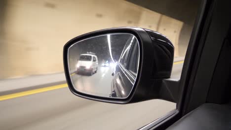 inside a tunnel looking in the side mirror of a car