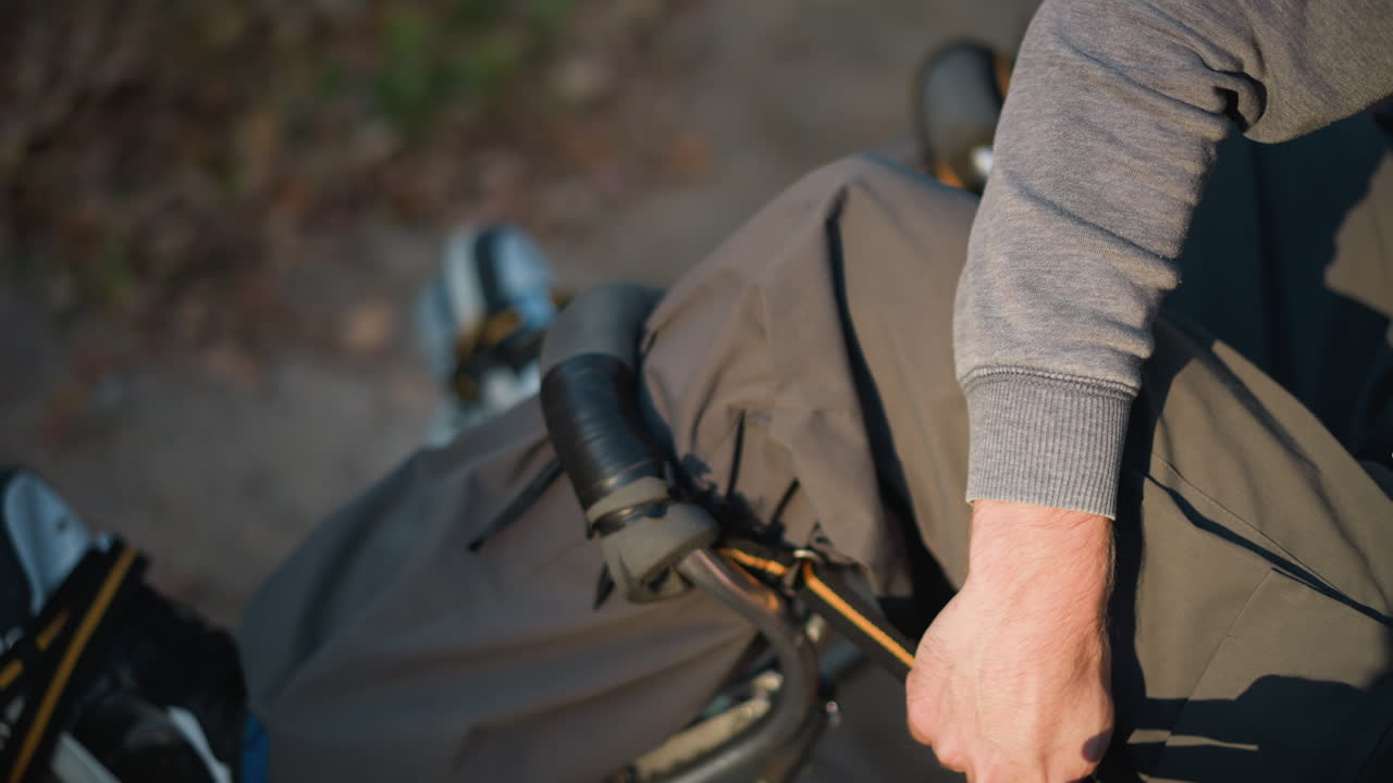 오리브 녹색 바지와 밝은 회색 스웨트 셔츠를 입고 자연 환경에서 안경을 조정하는 사람의 손의 클로즈업