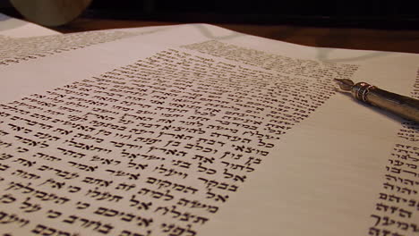 yad points to hebrew in torah on bimah, close up