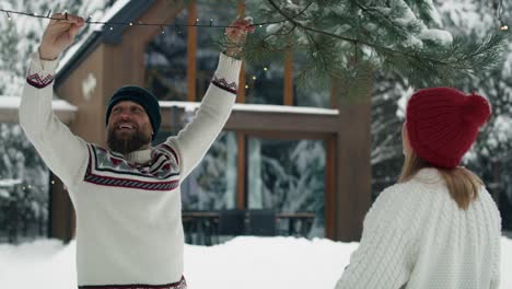 caucasian couple decorating garden by christmas in lights outdoors.