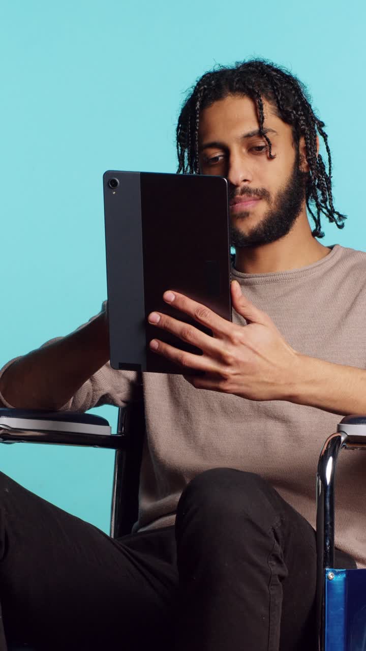 Vertical video Person with disability doing digital art on drawing tablet, studio background