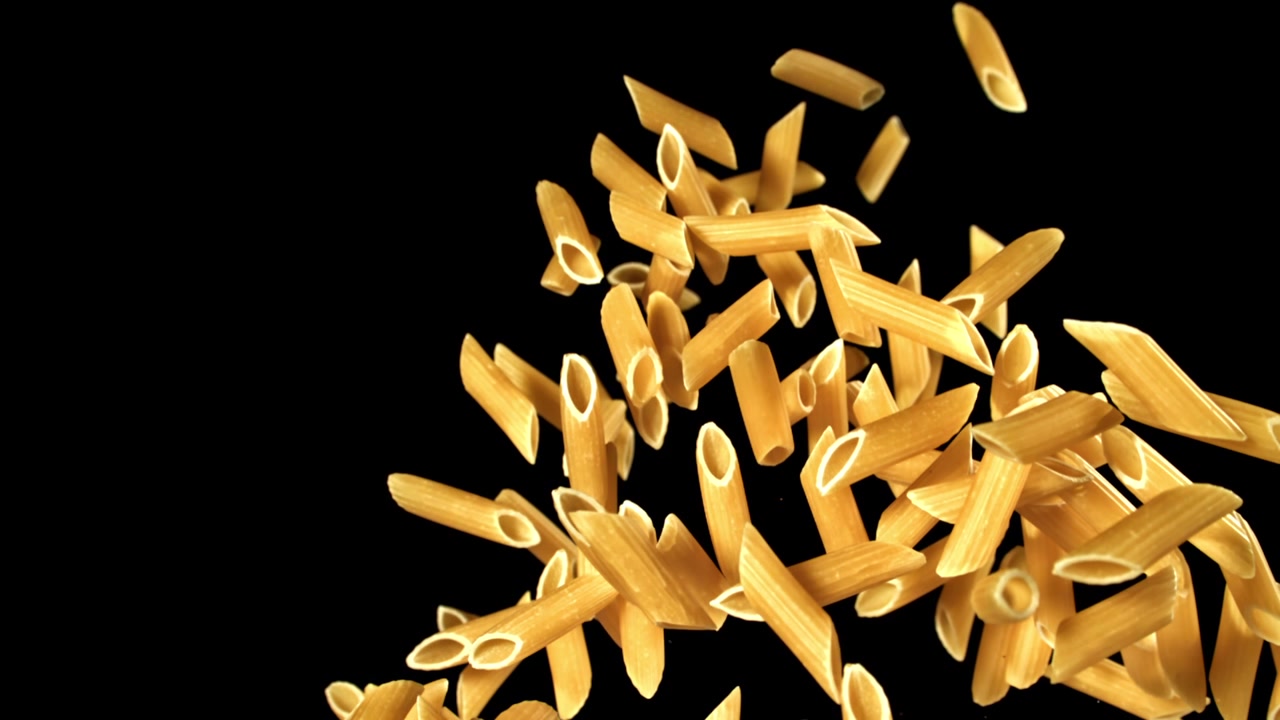 Penne secche che cadono e galleggiano al rallentatore su sfondo nero