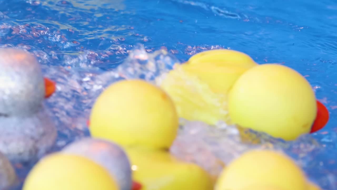 Yellow and glittery ducks bob and splash in vibrant blue water, creating a playful and lively scene.