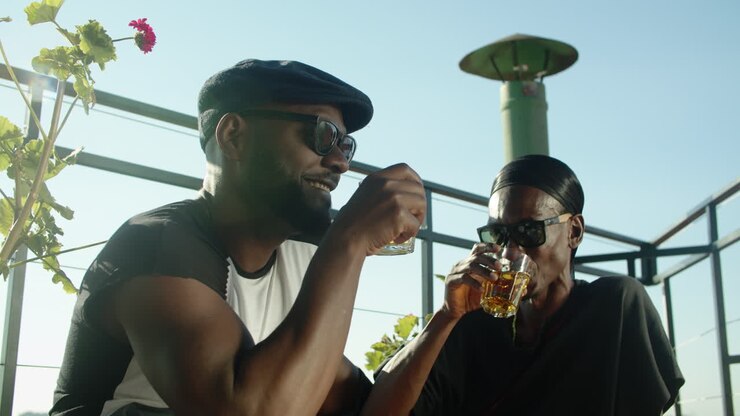 Homosexual lovers sitting on rooftop and drinking alcohol