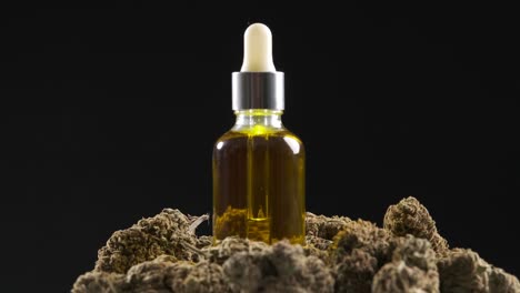 marijuana buds with a bottle of cbd hemp oil on a darkness background.